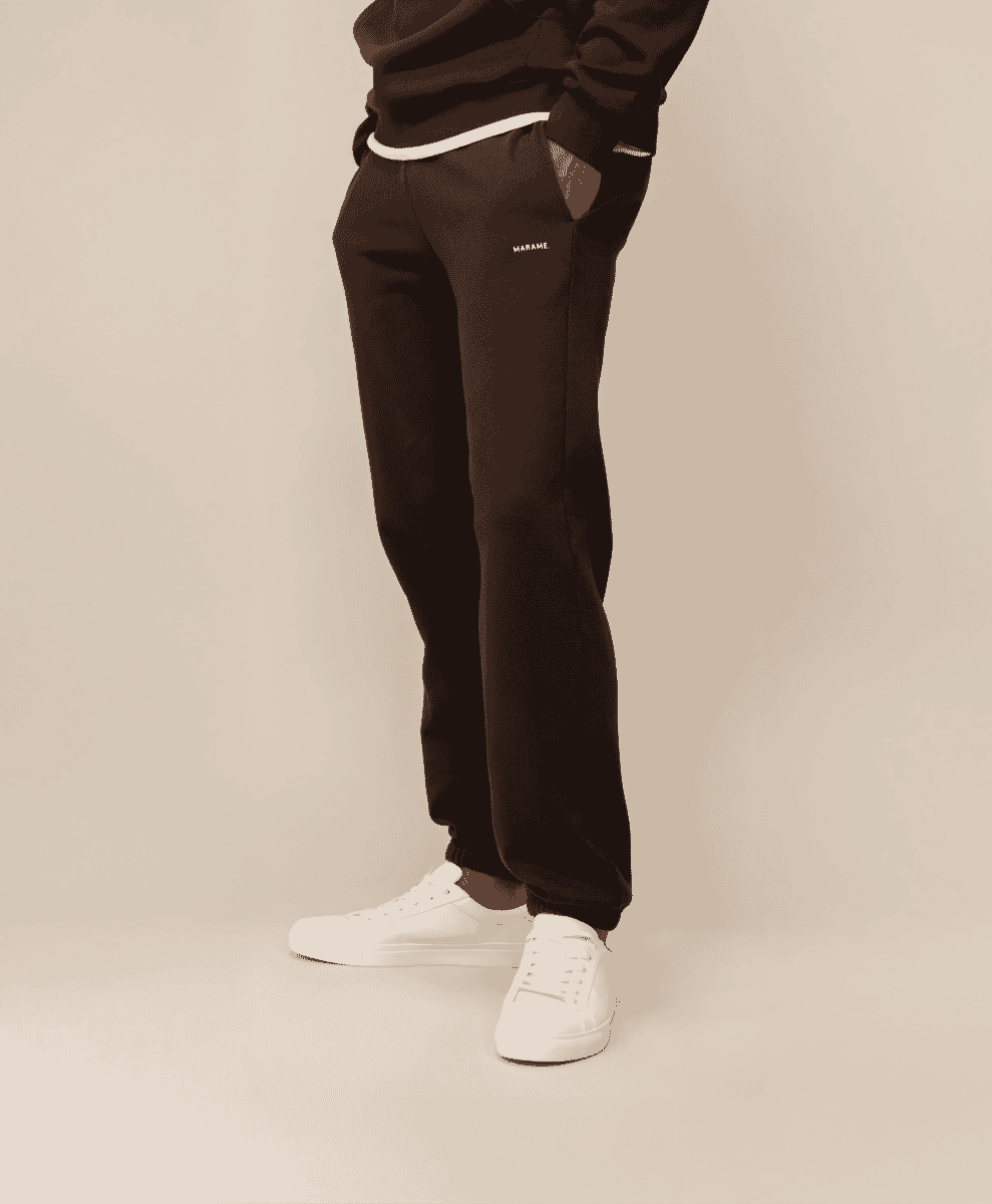 A person wearing dark brown sweatpants with a small 'MARAME' logo on the thigh.