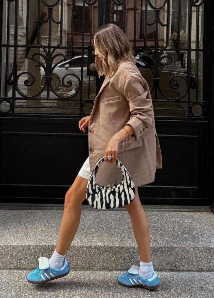 Street style shot of an influencer wearing vibrant sneakers paired with a fashion-forward outfit.