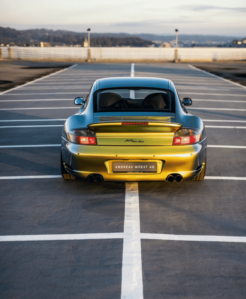 Rear view of a gold and blue Porsche showing dual exhausts and R-Turbo badging.