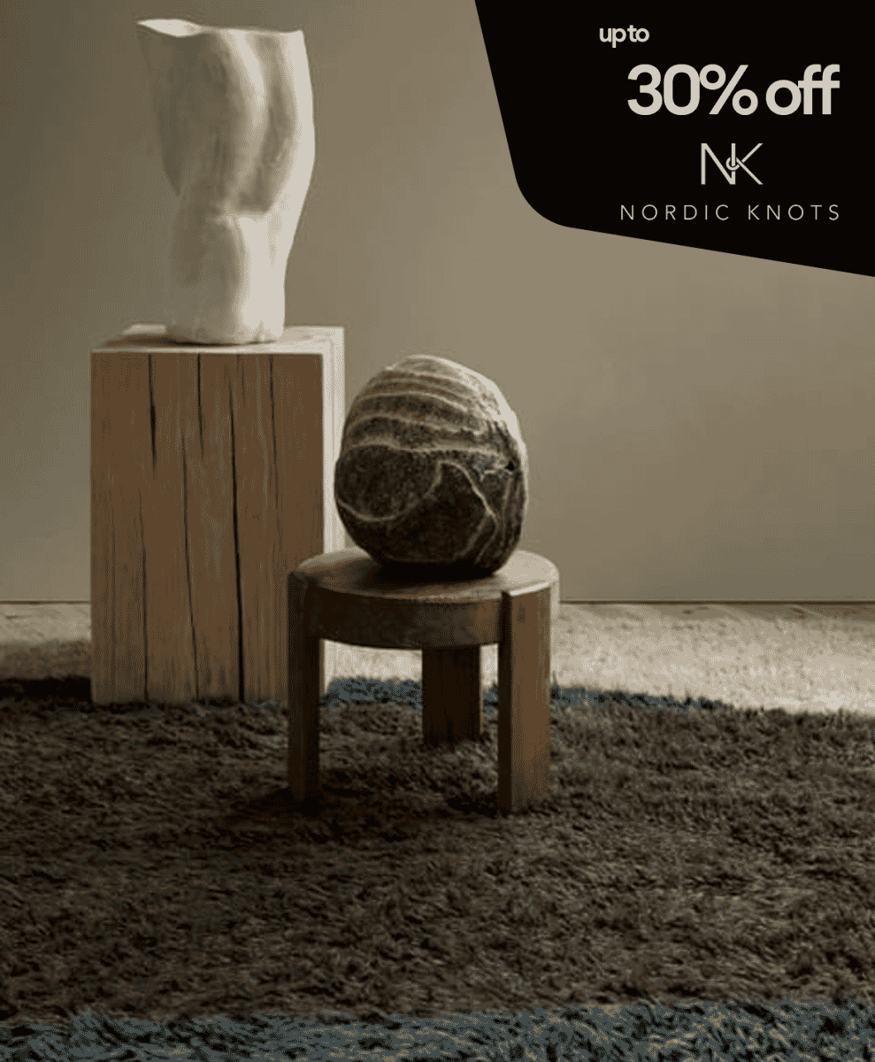 A minimalist interior with a stone sculpture, abstract vase, and plush rug.