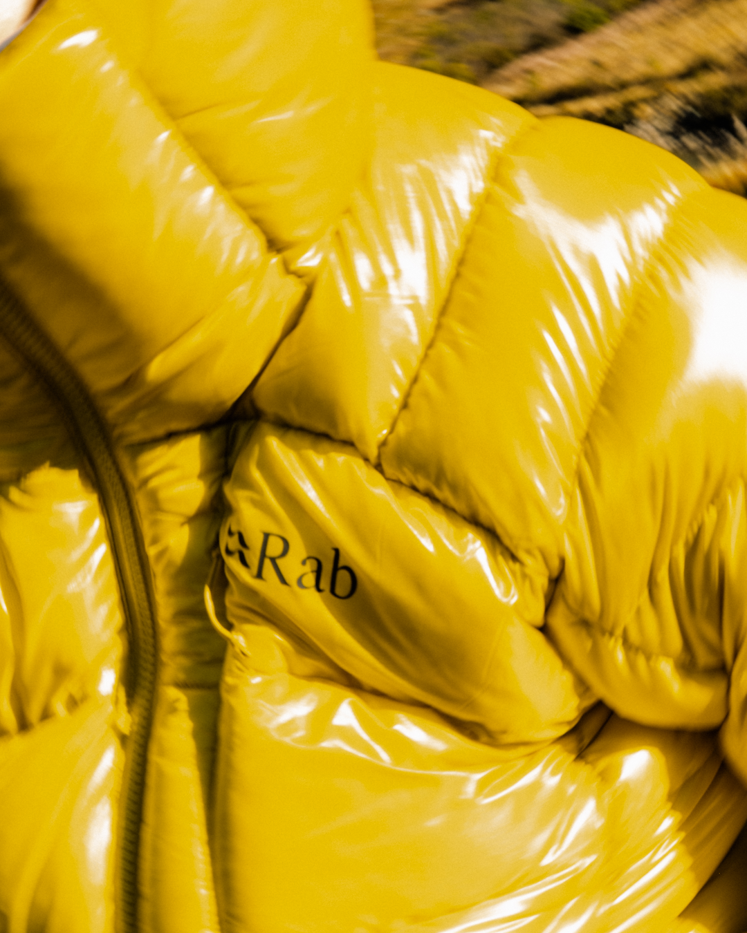 Close-up of a glossy yellow Rab puffer jacket with technical quilted stitching.
