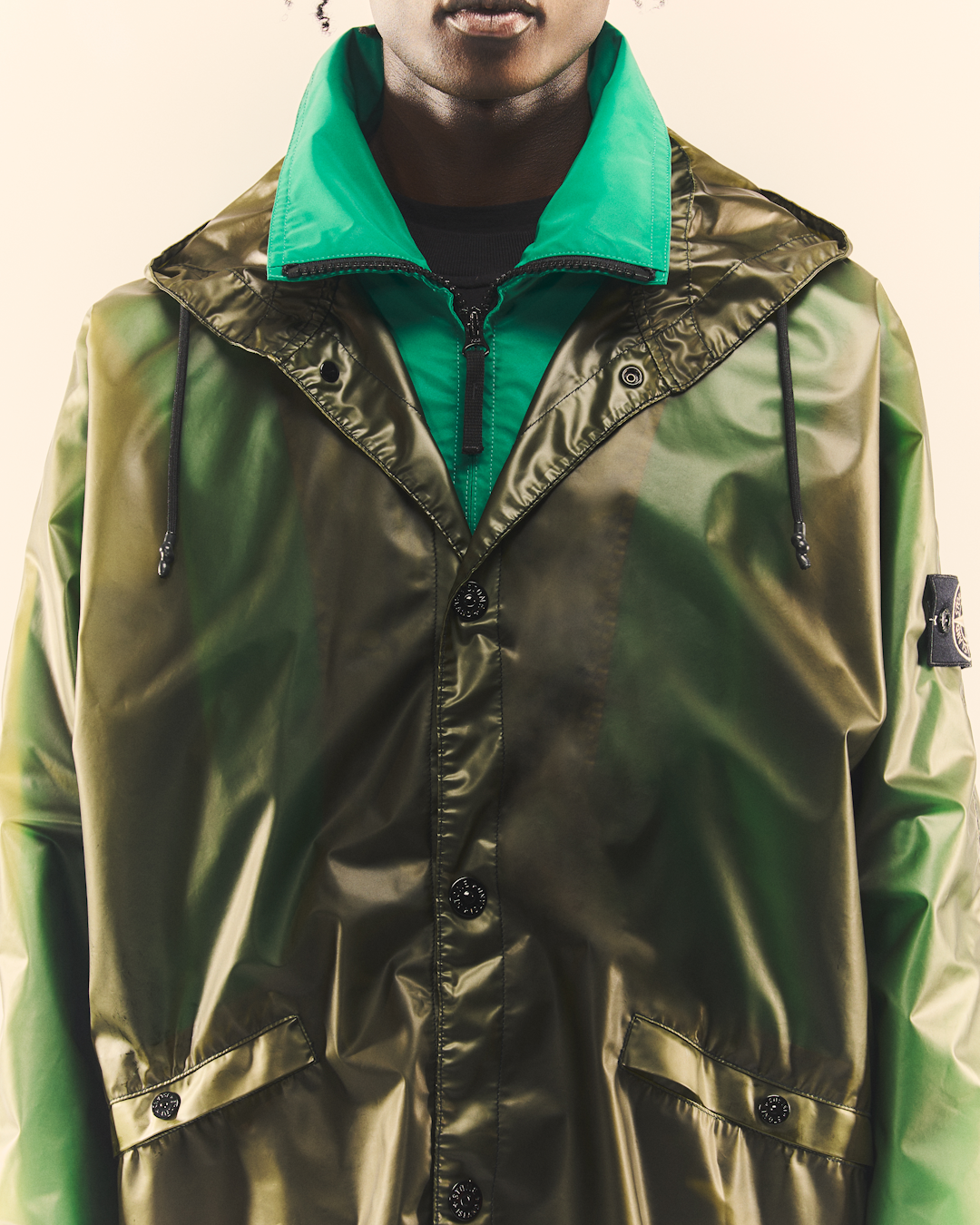 Close-up of the glossy green hooded jacket highlighting the bright green inner lining and collar details.