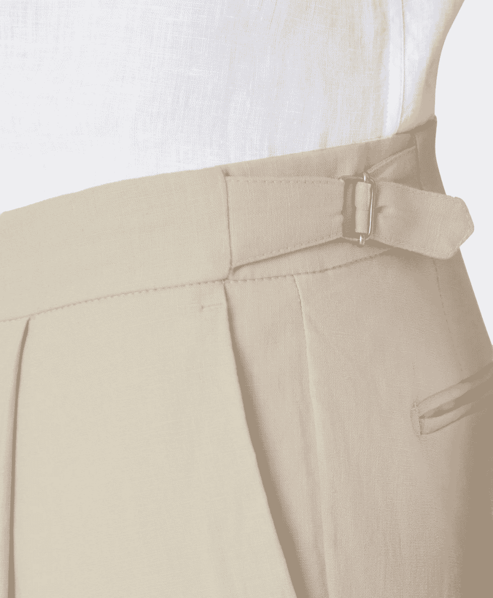 Close-up of beige pleated linen trousers with a matching belt and metal buckle.
