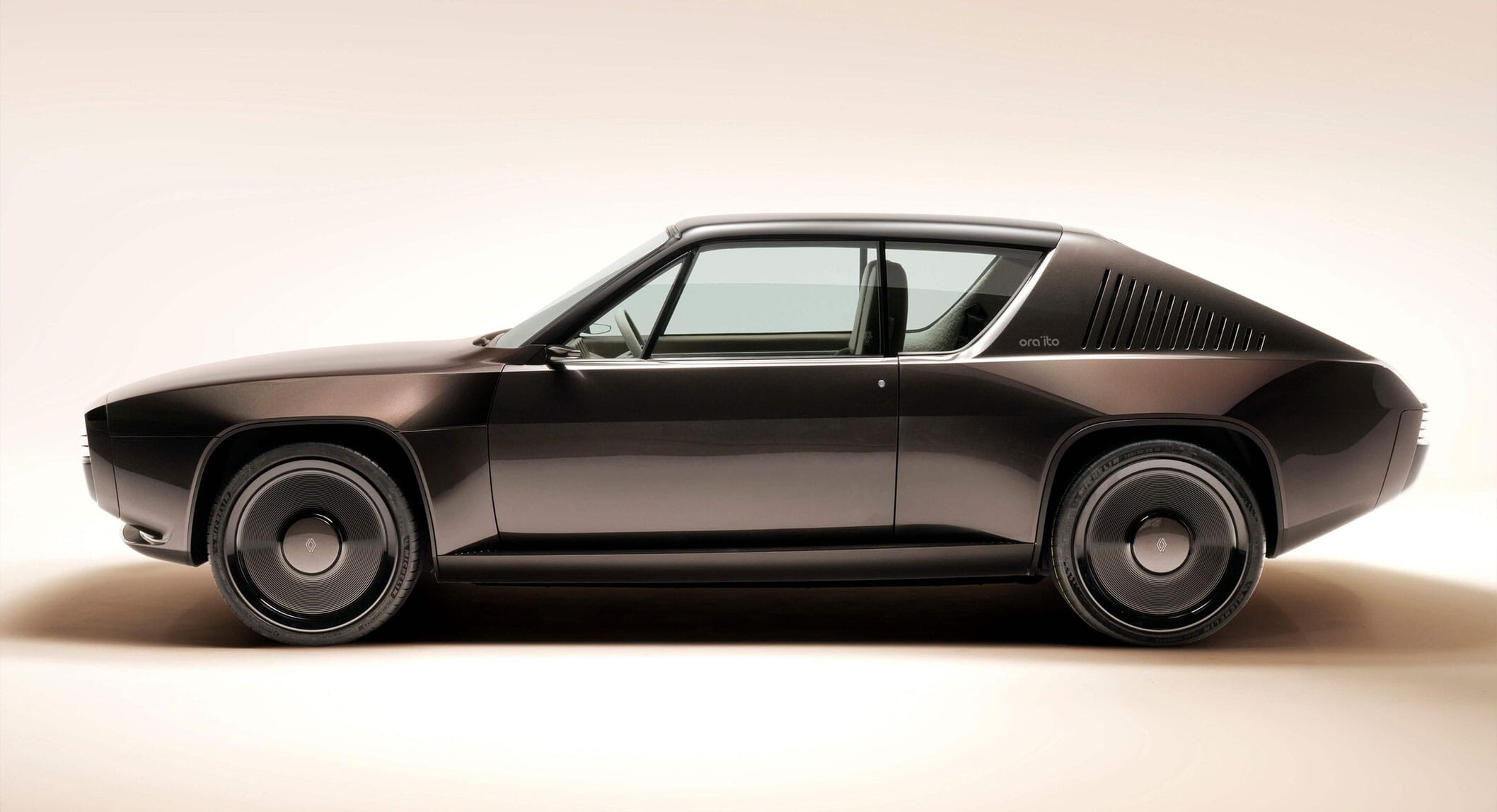 Low-angle studio shot of the dark metallic Renault R17 concept showing its sleek retro-futuristic profile.