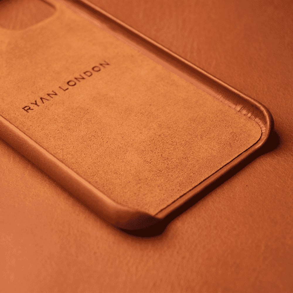 Macro shot of a tan leather phone case highlighting the 'RYAN LONDON' branding and leather texture.
