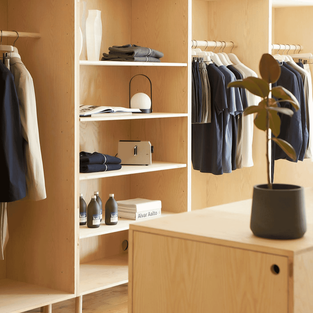 A minimalist wooden closet featuring neatly arranged men's apparel, folded sweaters, and accessories.