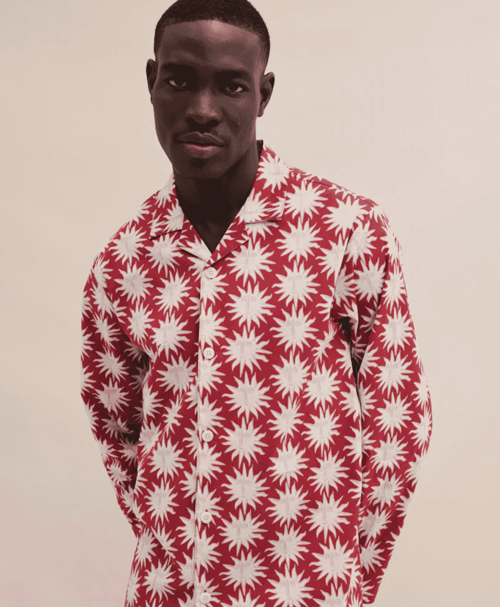 A man wearing a bold red shirt with a white sunburst face pattern.