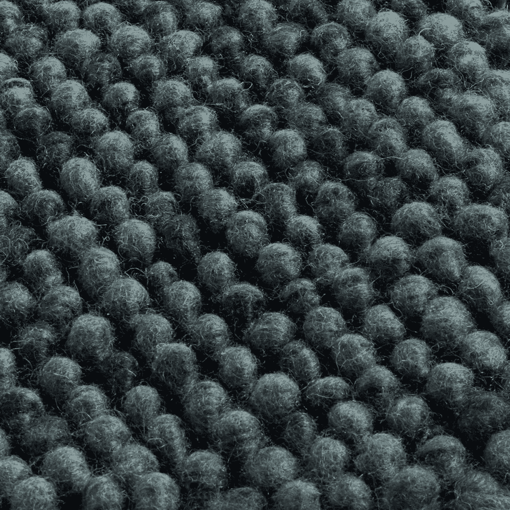 Macro detail of dark gray felted wool fabric with rounded tufts and a heavy texture.