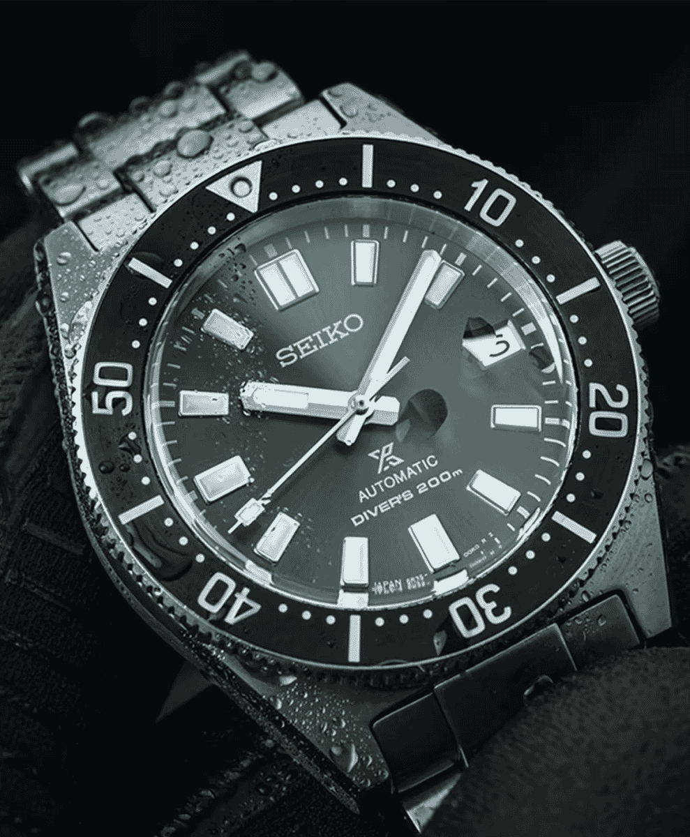 Macro shot of a Seiko diver watch with water droplets on the crystal and bezel.