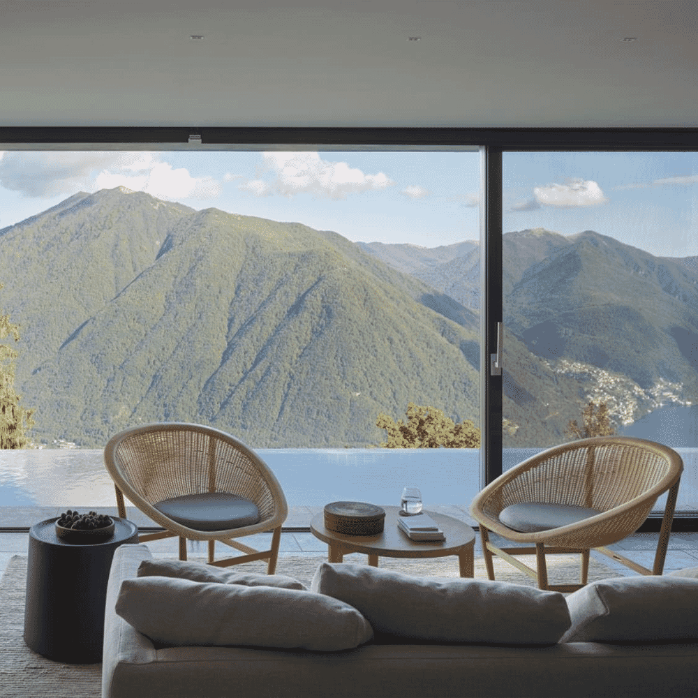Minimalist modern living room with large glass windows framing a mountain vista.