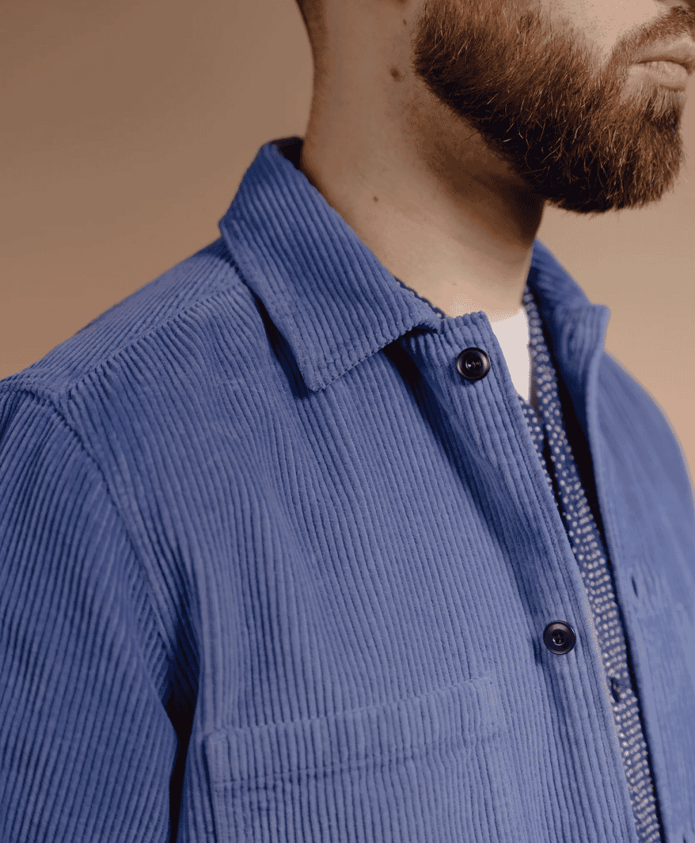 Close-up of a blue corduroy shirt layered over a patterned garment.